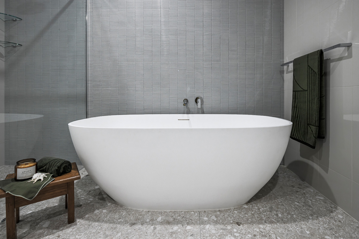renovated bathroom with featured kitkat tiles in light grey, chrome tapware and large self-standing bathtub