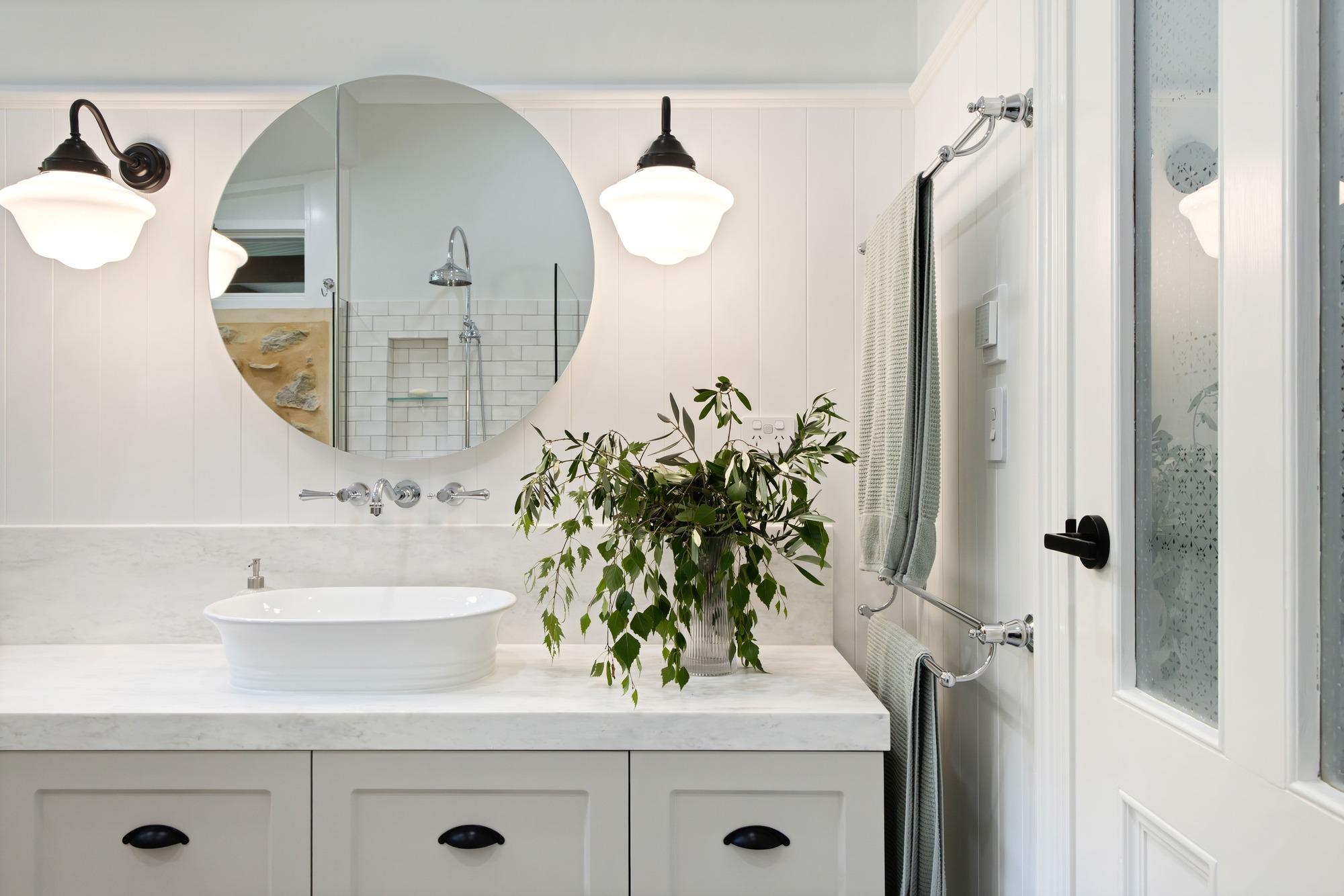 Classic Hamptons Style Bathroom with Carrera Benchtop, V-Jay Panelling, Vanity with Shaker Cabinet Profiles, Classic Chrome Accessories and Traditional Wall Pendants.
