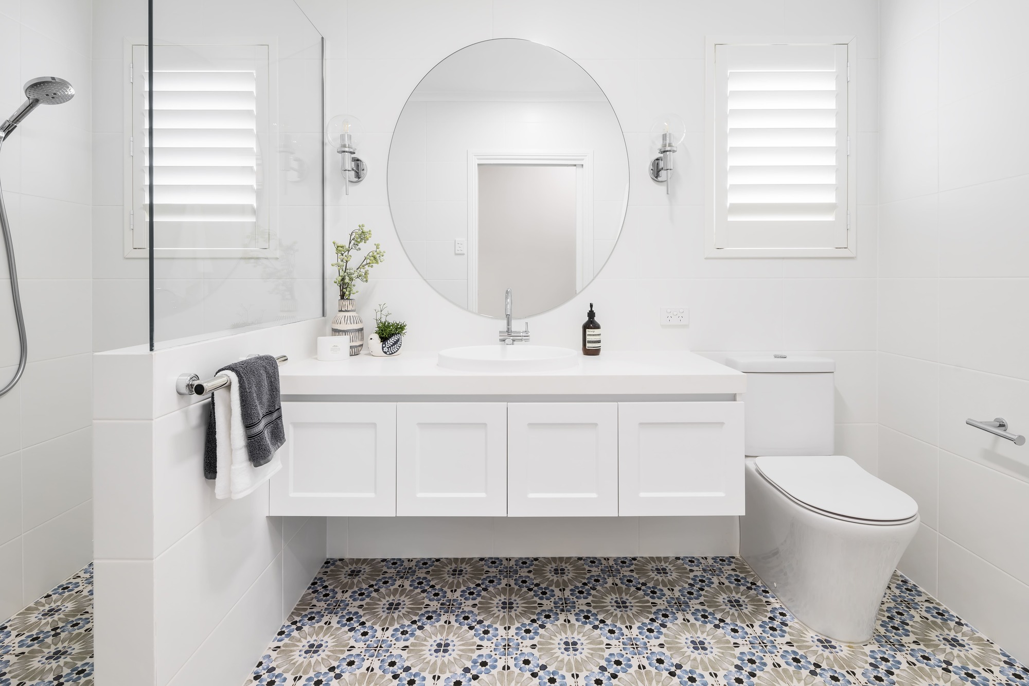 Hamptons Style Bathroom with Mosaic Floor Tiles, Vanity with White Shaker Cabinets, Walk-in Shower, Chrome Accessories and Clear Glass Wall Sconces