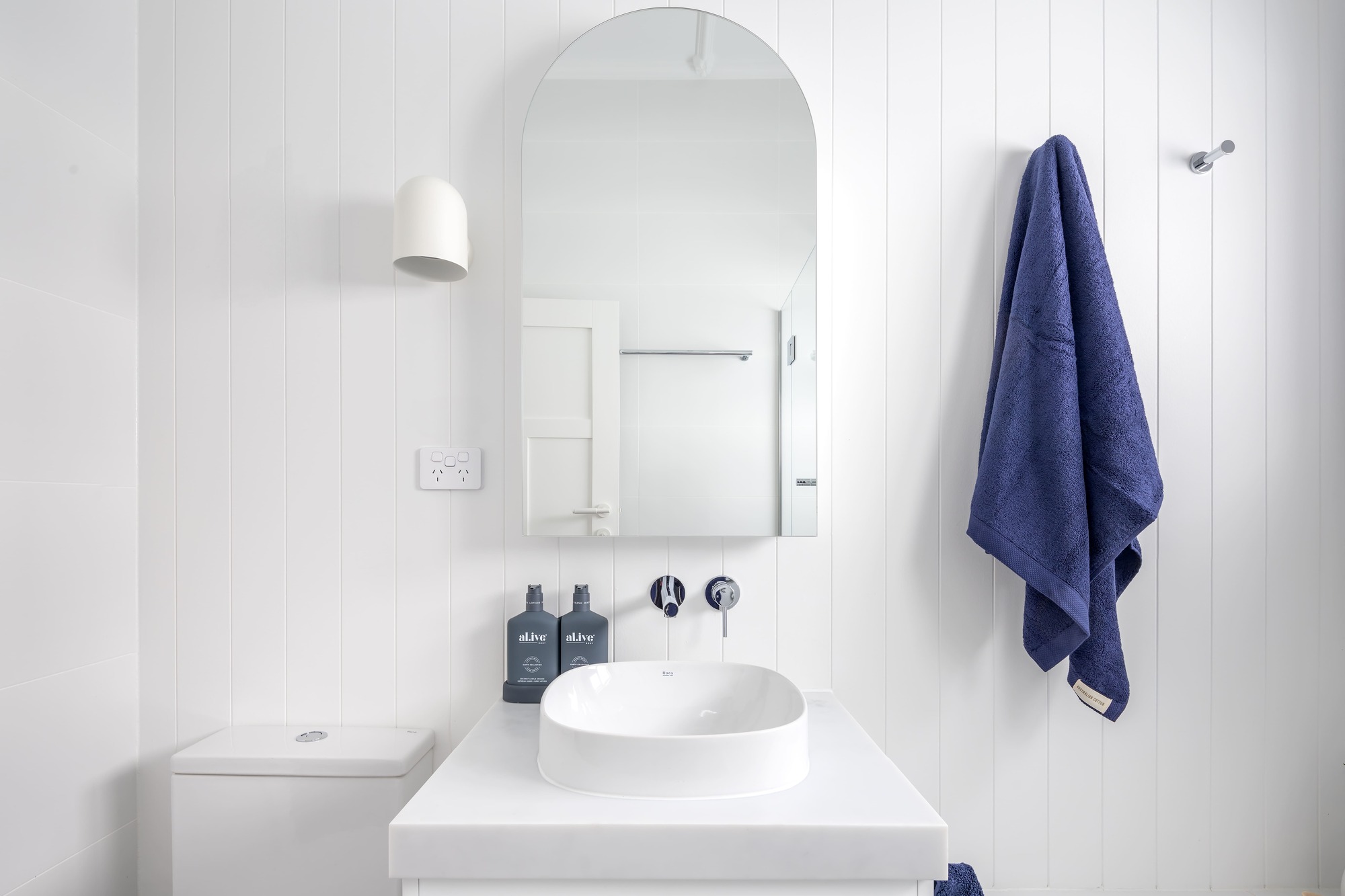 Hamptons Style Bathroom with V-Jay Panelling, Chrome Accessories, Frameless Mirror Cabinet, Carrera-Looking Benchtop and a Wall Sconce