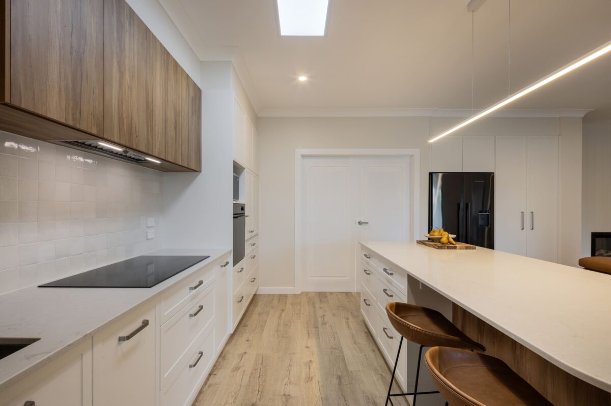 renovated kitchen open plan design with bespoke joinery, kitchen island with functional storage, ceiling skylight, induction cooktop