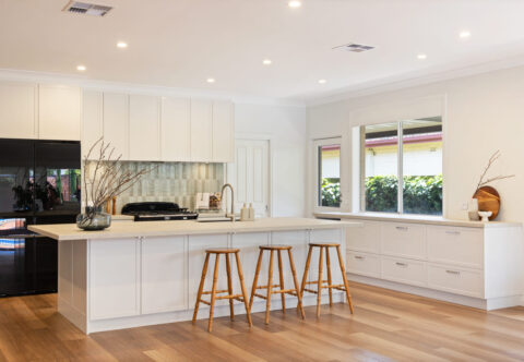 beautiful renovated large kitchen with 3-meter island, porcelain benchtops, blue tiled splashback, vinyl flooring and gas cooktop