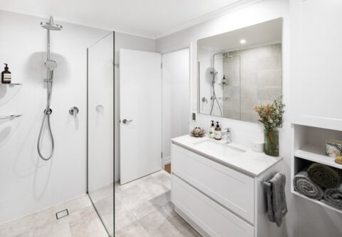 renovated bathroom with walk-in shower, chrome fixtures, while shaker cabinetry and engineered stone benchtops