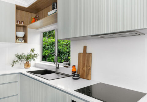 renovated compact kitchen with mid-century style, bespoke joinery with grooved profiles and black fixtures