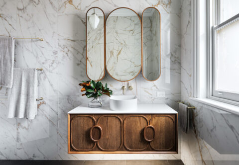 renovated bathroom with art-deco style, marble looking wall tiles, curved mirrors and decorative vanity