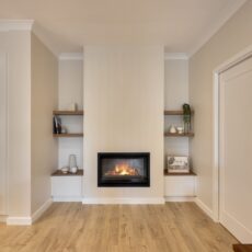 renovated living room, VJ panelling with gas fireplace, custom cabinetry and floating shelves.
