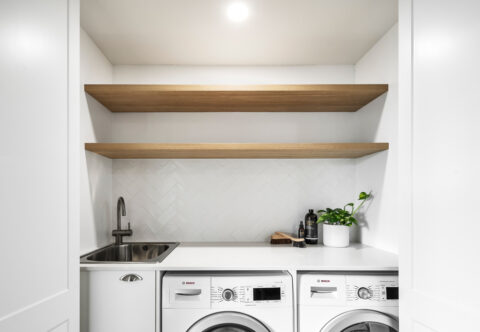 renovated laundry, European style with sliding bi-fold doors, with natural oak open shelving, LED strip lighting and washer and dryer