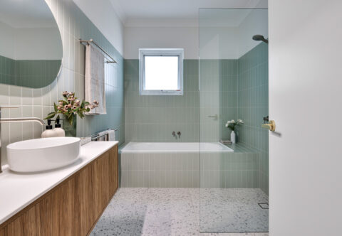 renovated bathroom, mid-century colourful, pistachio-coloured wall tiles and terrazzo floor tiles, wall hung vanity and back-lid mirror