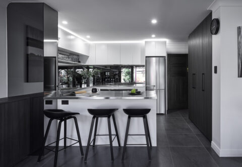 renovated kitchen, stainless steel benchtops and mirror splashback, breakfast bar, bespoke joinery with built-in appliances