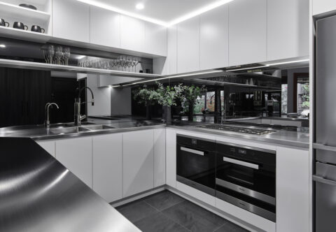 renovated kitchen, stainless steel benchtops and mirror splashback, breakfast bar, bespoke joinery with built-in appliances