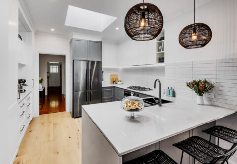 renovated kitchen with bespoke joinery, tiles splashback, stone benchtops, skylight and stainless-steel appliances