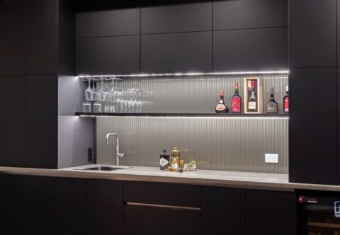 Renovated home theatre and bar with bespoke joinery in black, with glass splashback, modern and minimalistic