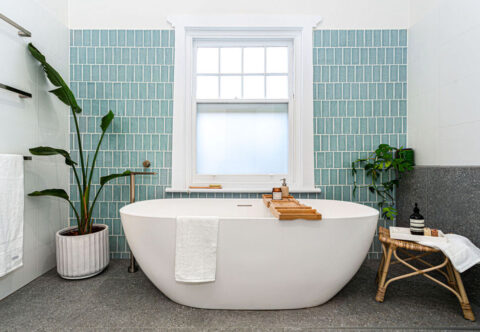 renovated bathroom, mis-century inspired with free-standing bathtub, features wall tiles in Turquoise colour paired with dark grey floor tiles and shower ledge.