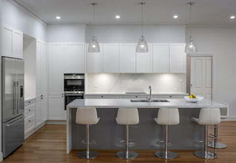 renovated kitchen with a contemporary, classic style, bespoke joinery, floating island with porcelain cladding on splashback and benchtops, pared with shaker cabinets and finished with glass pendants