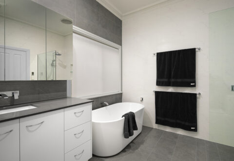 renovated bathroom with free standing bath, open walk-in shower, wall hung mirrored shaving cabinets with vanity storage beneath in warm grey tones