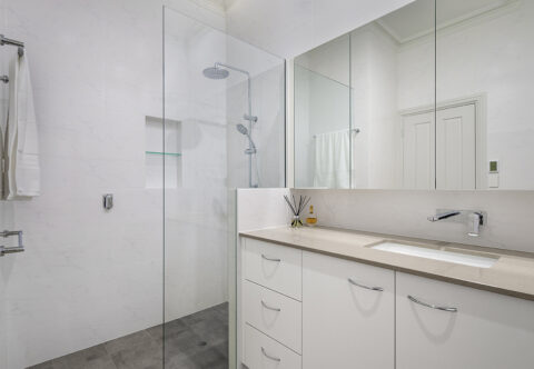 renovated bathroom with walk-in, open shower, wall niche and mirrored wall cabinets with internal power point, stone bench tops and underfloor heating.