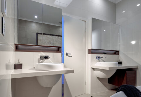 renovated bathroom, his and hers vanities with floating vessels on solid surface benchtops, recessed mirror cabinets, floor-to-ceiling tiling and underfloor heating