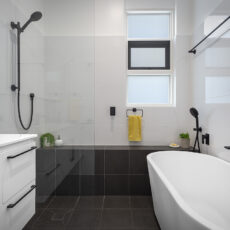 renovated bathroom, monochromatic with free standing bathtub, shower bench seat and open walk-in shower.