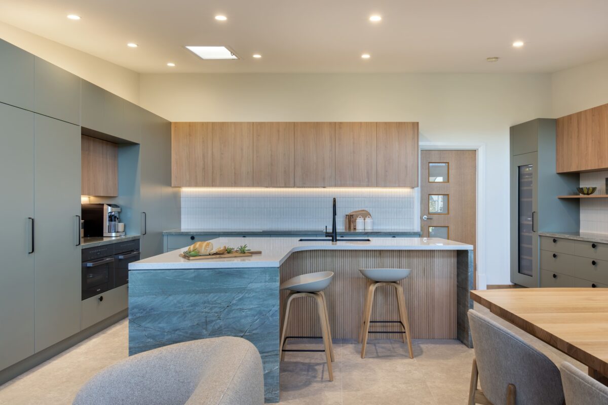 renovated kitchen, and living room of 1920s California Bungalow, beautiful green cabinetry paired with Tasmanian oak and Emerald Green natural Quartzite and black fixtures and fittings.
