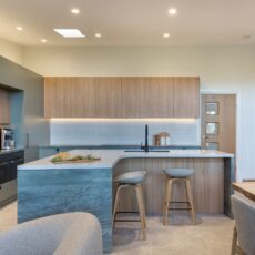 renovated kitchen, and living room of 1920s California Bungalow, beautiful green cabinetry paired with Tasmanian oak and Emerald Green natural Quartzite and black fixtures and fittings.