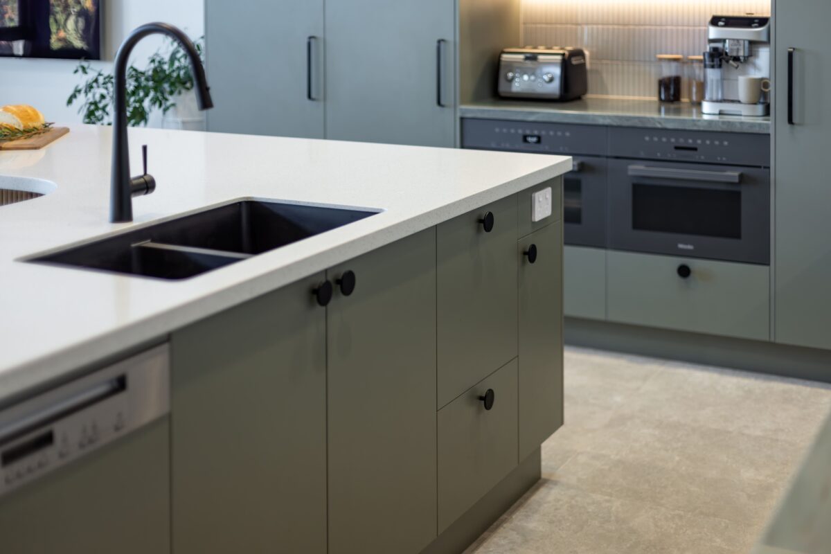 renovated kitchen, contemporary style, beautiful green cabinetry paired with white solid surface acrylic benchtop and black fixtures and fittings.