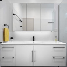 renovated bathroom, with large vanity, mirror cabinets, using black fixtures and fittings and white cabinetry.