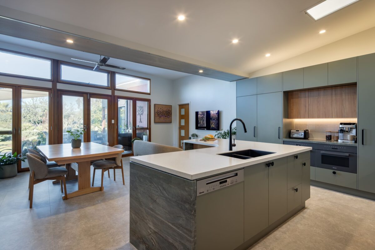 renovated kitchen, and living room in Cowandilla, designed and built by Brilliant SA Renovations, it features a with large kitchen island with Emerald Green Quartzite on island waterfall ends and solid surface acrylic benchtop.