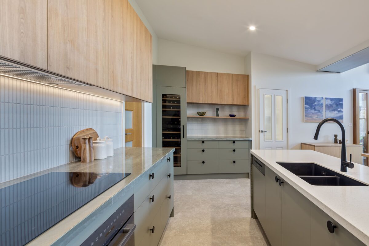 renovated kitchen, and living room of 1920s California Bungalow, beautiful green cabinetry paired with Tasmanian oak, an integrated wine fridge, open shelves and pretty of storage.