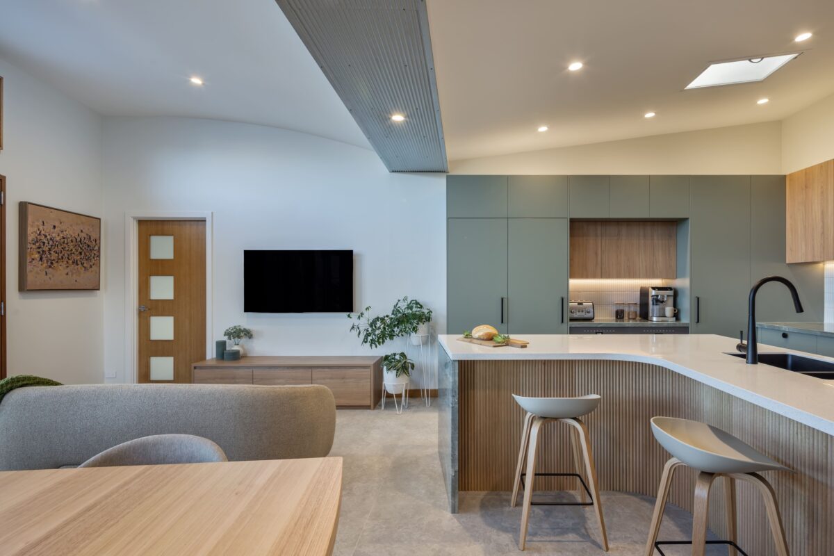 renovated kitchen, and living room of 1920s California Bungalow, beautiful green cabinetry paired with Tasmanian oak and solid surface acrylic benchtop.
