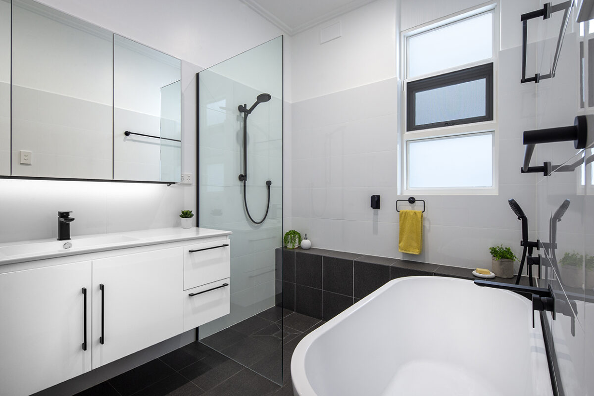 renovated bathroom, monochromatic with large vanity, mirror cabinets, free standing bathtub, shower bench seat and open walk-in shower.