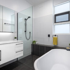 renovated bathroom, monochromatic with large vanity, mirror cabinets, free standing bathtub, shower bench seat and open walk-in shower.