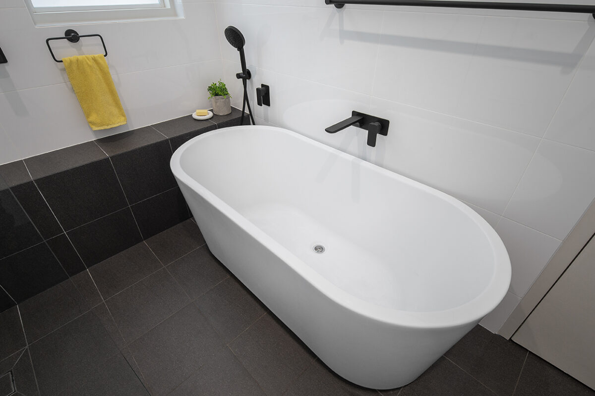 renovated bathroom, monochromatic with free standing bathtub, shower bench seat and open walk-in shower.