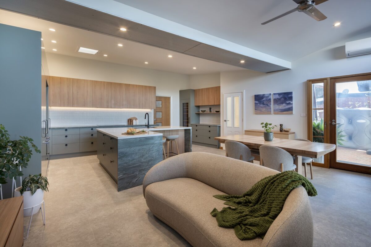 renovated kitchen, and living room of 1920s California Bungalow, beautiful green cabinetry paired with Tasmanian oak and Emerald Green natural Quartzite and black fixtures and fittings