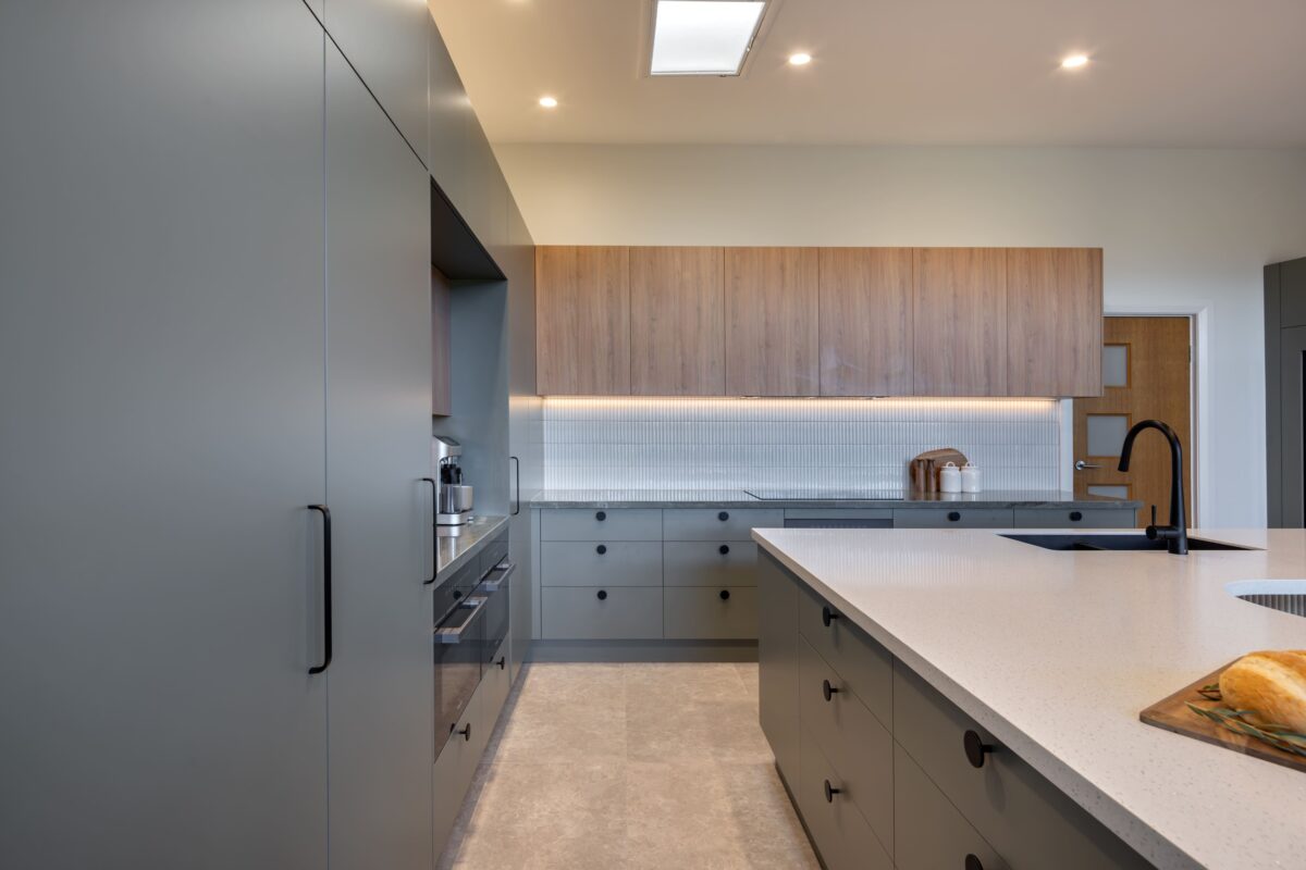renovated kitchen, and living room of 1920s California Bungalow, beautiful green cabinetry paired with Tasmanian oak, Emerald Green natural Quartzite and solid surface acrylic benchtop.