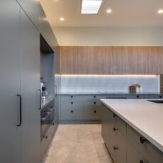 renovated kitchen, and living room of 1920s California Bungalow, beautiful green cabinetry paired with Tasmanian oak, Emerald Green natural Quartzite and solid surface acrylic benchtop.