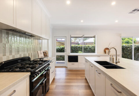 beautiful renovated large kitchen with 3-meter island, porcelain benchtops, blue tiled splashback, vinyl flooring and gas cooktop