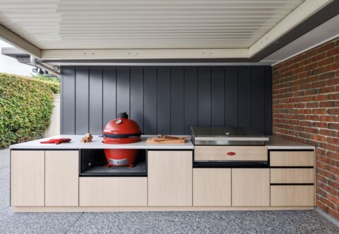 renovated outdoor kitchen with minimalistic alfresco area, concrete benchtop, custom cabinetry and red oval smoker and grill.