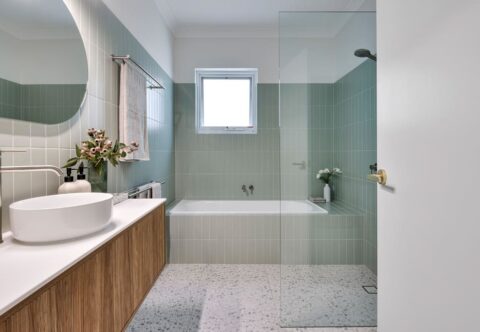 renovated bathroom, mid-century colourful, pistachio-coloured wall tiles and terrazzo floor tiles, wall hung vanity and back-lid mirror