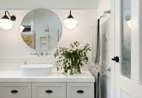renovated bathroom, traditional country style, VJ panelling, patterned porcelain floor tiles, wall-hung vanity with marble-look benchtop, round mirror cabinet and black accents.