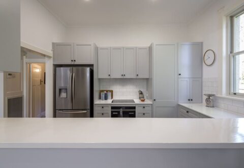 Renovated kitchen, traditional style with functional U-shape layout and custom joinery, stone benchtops and matte black doorknobs.