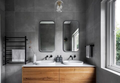 renovated bathroom with floating vanity, heated towel rails, twin mirrors, dark polished tapware, solid wood cabinetry and engineered stone benchtops