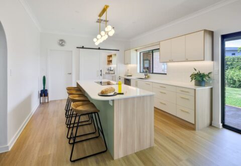 renovated kitchen, retro style with breakfast bar on kitchen island light pendant, bespoke joinery in green, white and wood finishes paired with brushed nickel handles