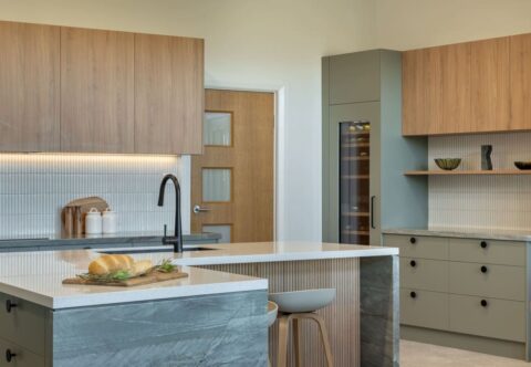 renovated kitchen, and living room of 1920s California Bungalow, beautiful green cabinetry paired with Tasmanian oak and solid surface acrylic benchtop.