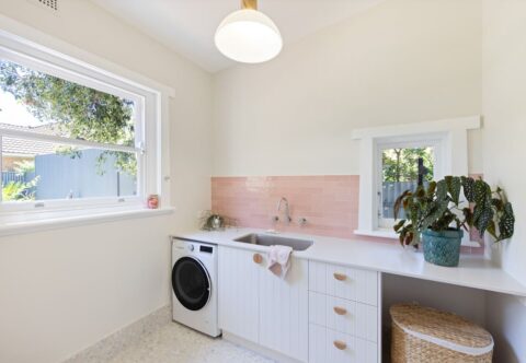 renovated laundry with pink splashback, white joinery, wooden handles and new appliances