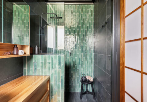 renovated bathroom with beautiful green feature tiles in a vertical off-set layout, black wall tiles, walk-in shower, natural wood vanity