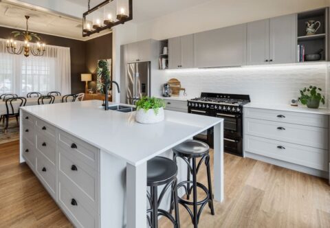 renovated kitchen, modern-traditional style with thermolaminated shaker profiles in light grey, traditional handle sand knobs in black, large island with stone tops. Structural changes made by a licenced builder -Brilliant SA Renovations.