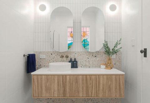 renovated bathroom, twin mirror cabinets, wall sconce, floating vanity with single basin, terrazzo looking floor tiles and white feature wall tiles.