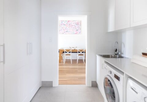 renovated laundry with bespoke joinery, tiled floor, engineered stone benchtops, washer and dryer