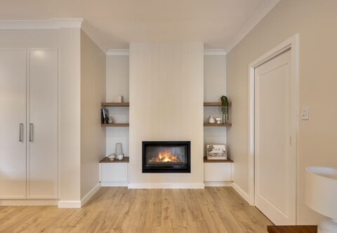 renovated living room, VJ panelling with gas fireplace, custom cabinetry and floating shelves.
