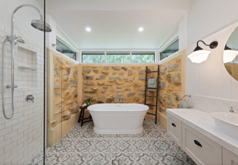renovated bathroom, traditional country style, patterned porcelain floor tiles, free-standing bathtub, traditional tapware, restored natural stone wall